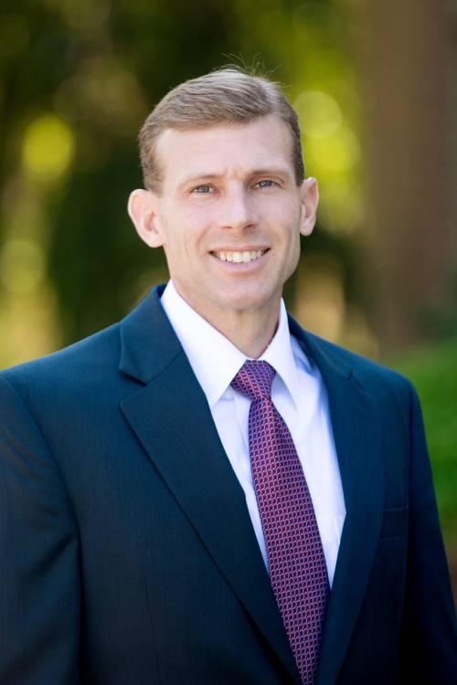 Professional man in a suit smiling outdoors.