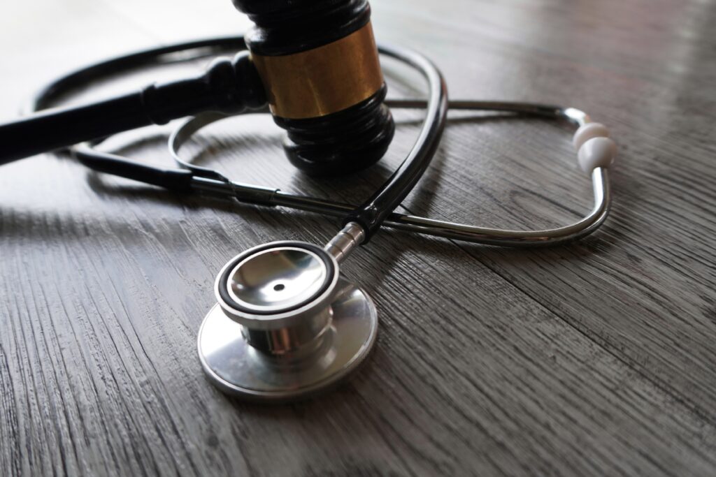 A stethoscope and a wooden gavel on a wooden surface.