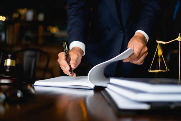 A person in a suit flipping through a notebook at a desk.